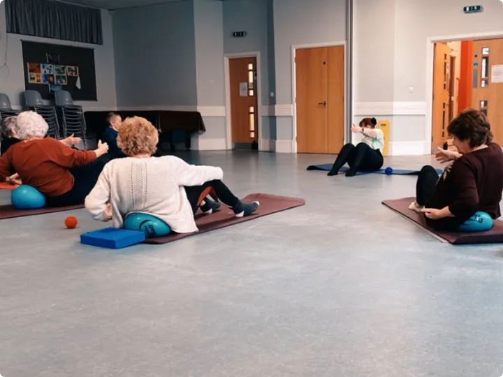 Over 60s exercise class using mats and soft balls in a community hall in Wokingham, Willing Spirit Exercise